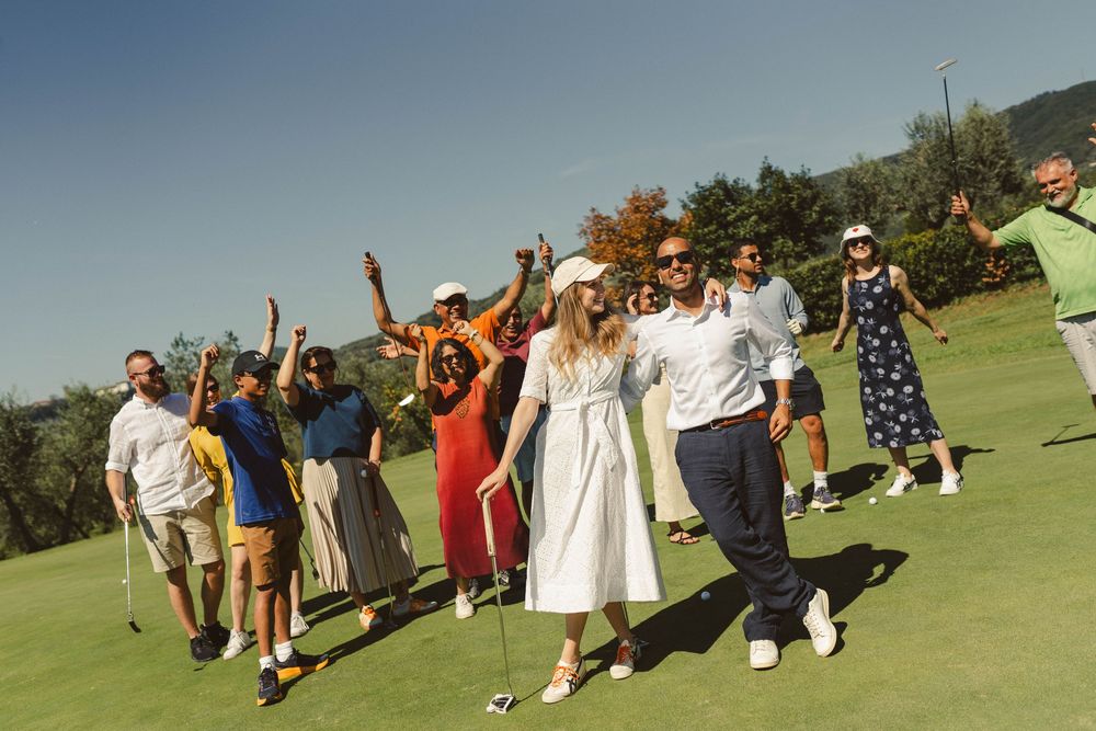 A cheerful group celebrating on a sunny golf course with raised arms.