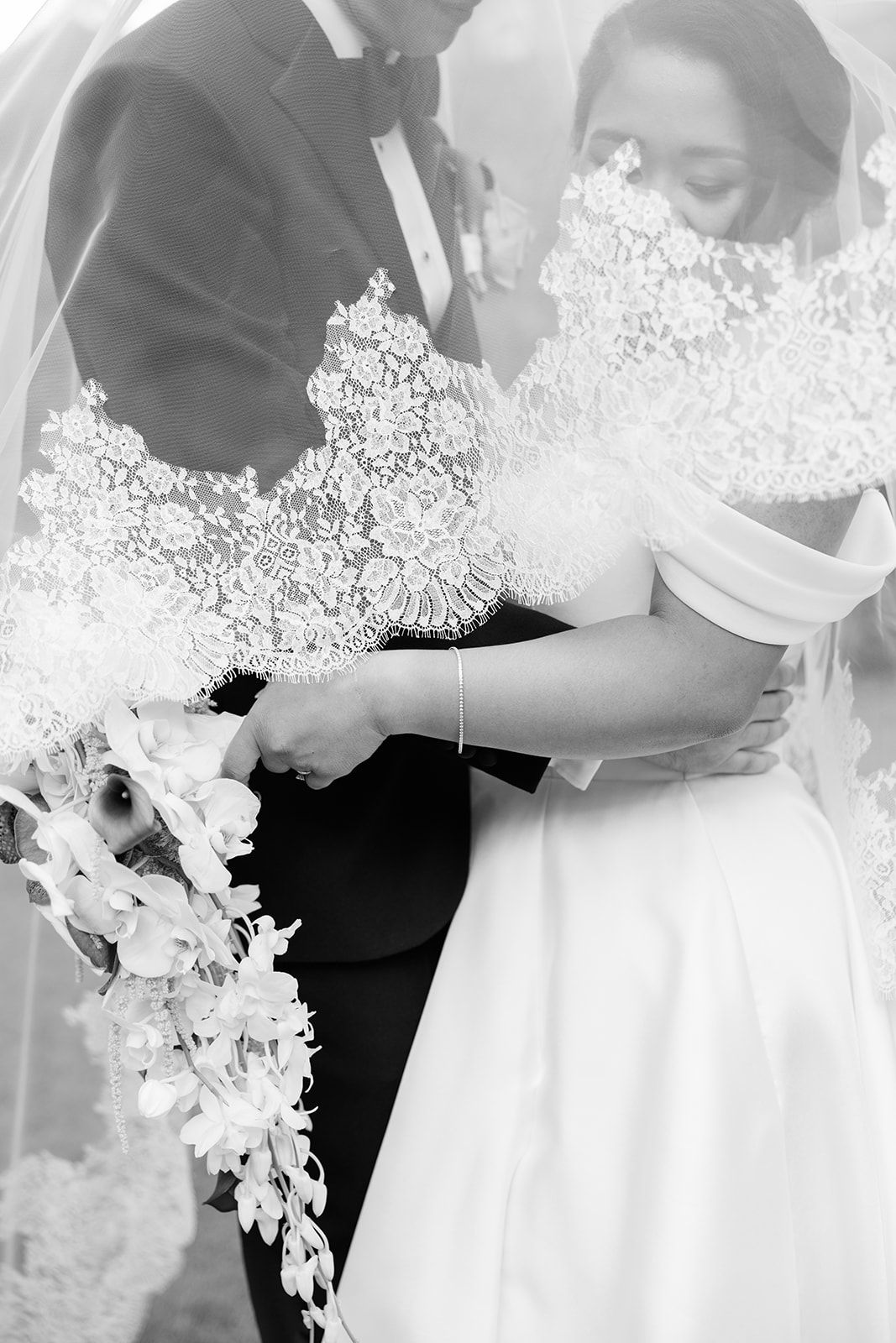 Black and white wedding photo series showing romantic close-up moments between newlyweds with white flowers and formal attire.