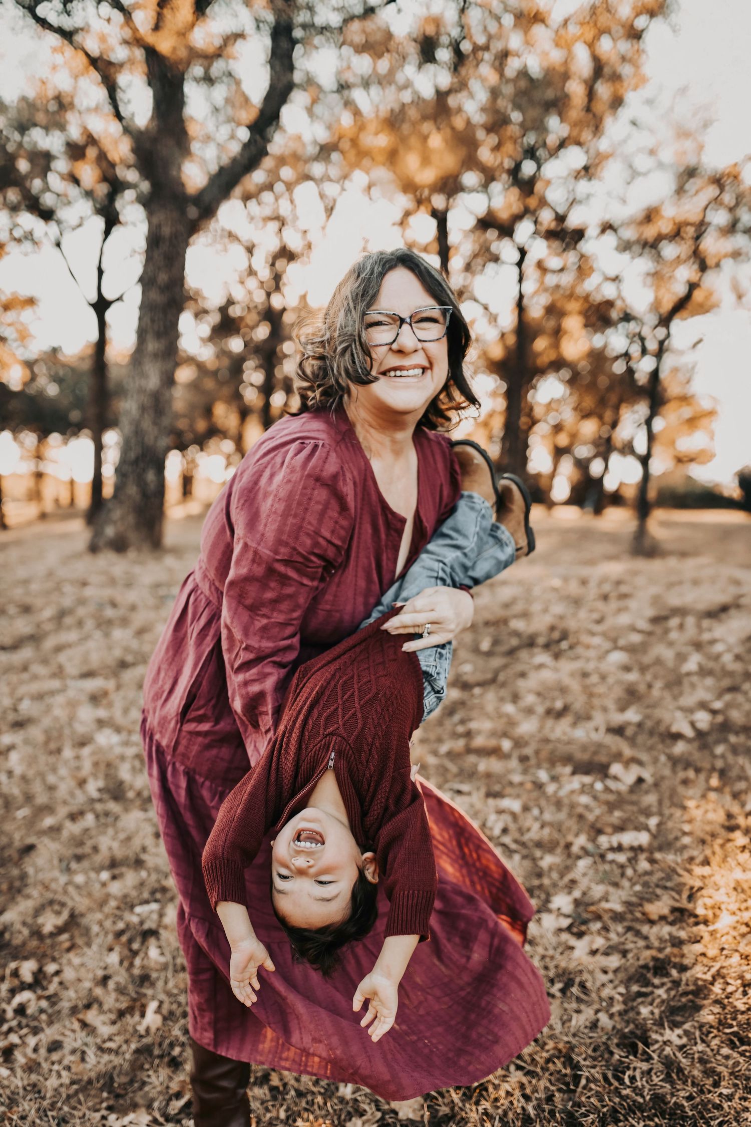 Candid moment between grandma and her two year old grandson playing in the woods at sunset