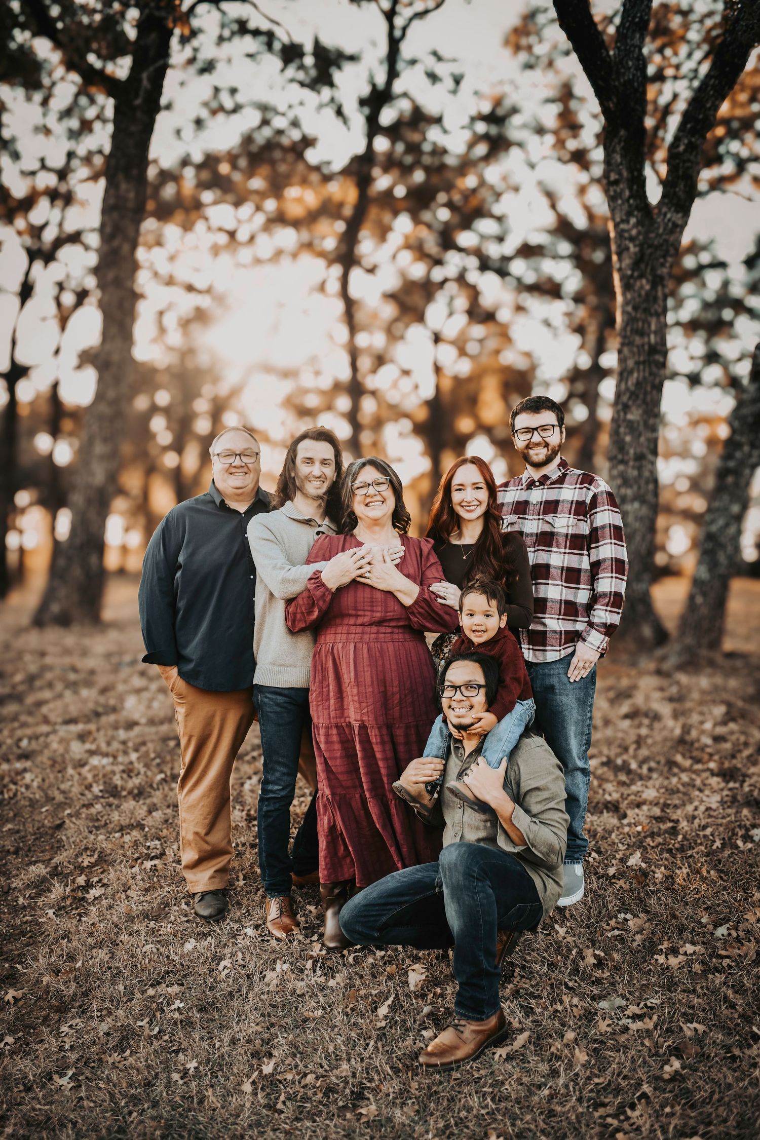 Candid family moment with toddler playing while adults laugh in warm sunset light.