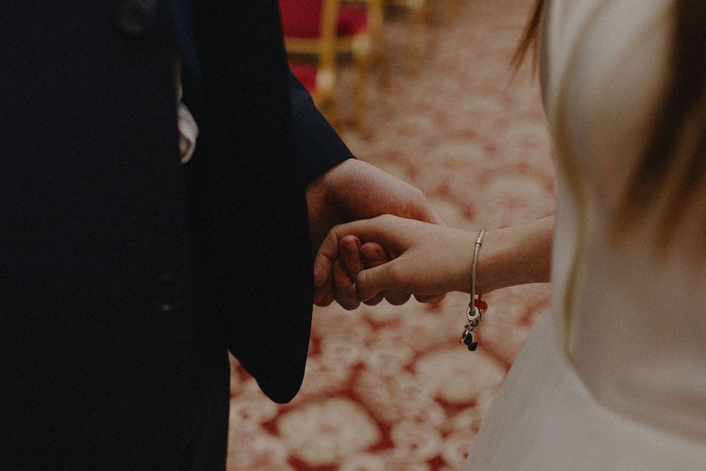 Close-up view of hands exchanging wedding rings during an intimate ceremony.