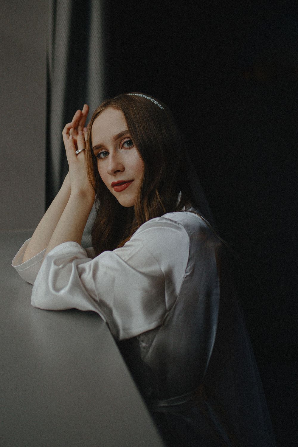 A series of moody portrait photographs showing a woman in a white shirt against a dark background with dramatic lighting.
