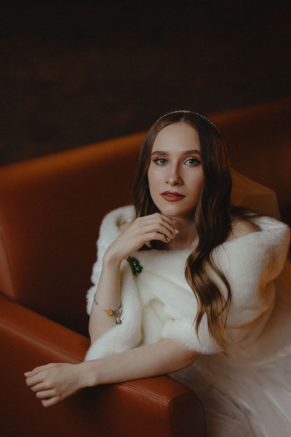 Artistic portrait series showing a person in a white sweater reclining on brown leather furniture in moody lighting.