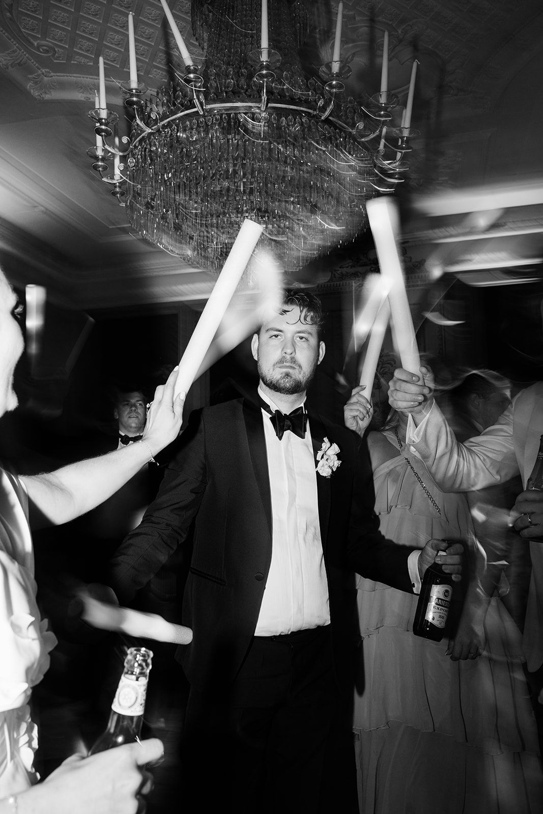 Wedding guests dance and celebrate on a dimly lit dance floor during an evening reception party.