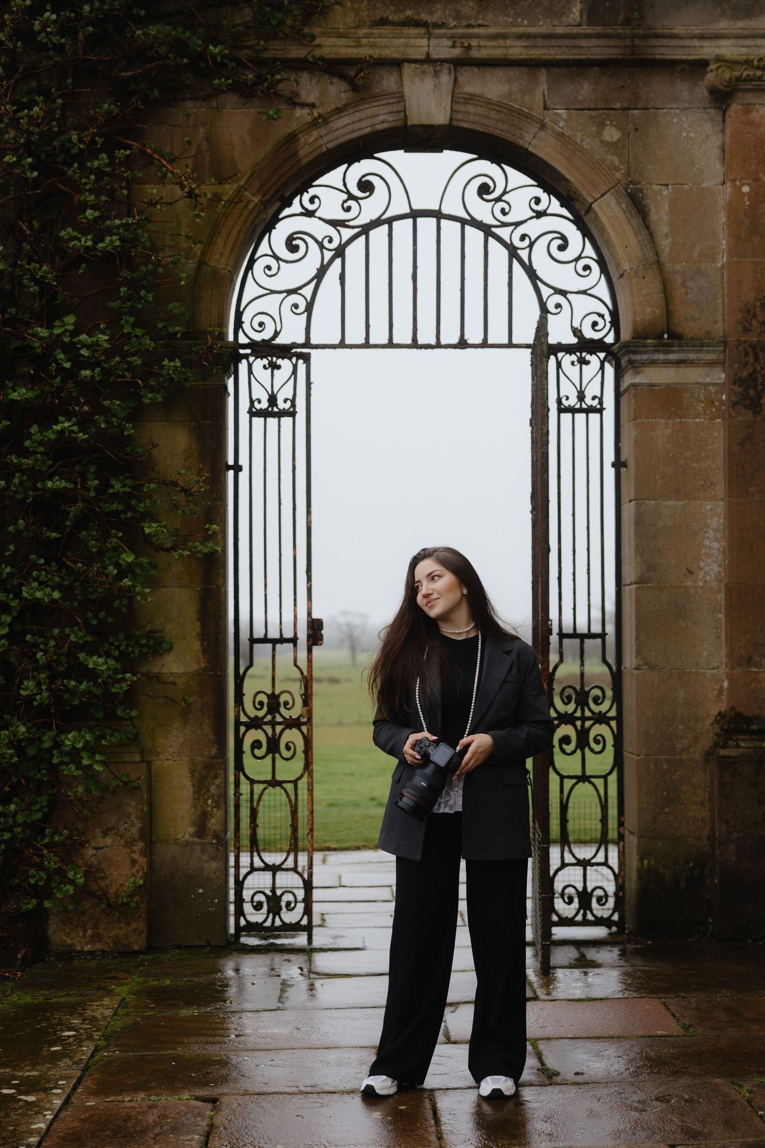 A person in a black blazer and white top sits contemplatively on stone steps in an urban setting.
