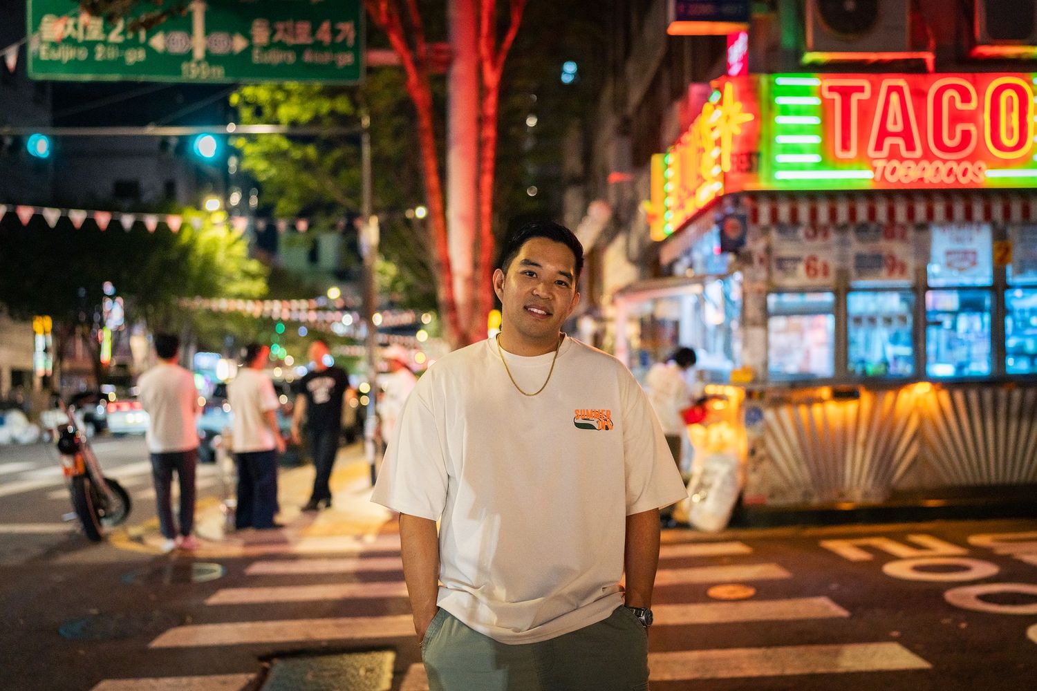 Vibrant nighttime street scene in Korea with illuminated storefronts and neon signs glowing in red and blue hues.