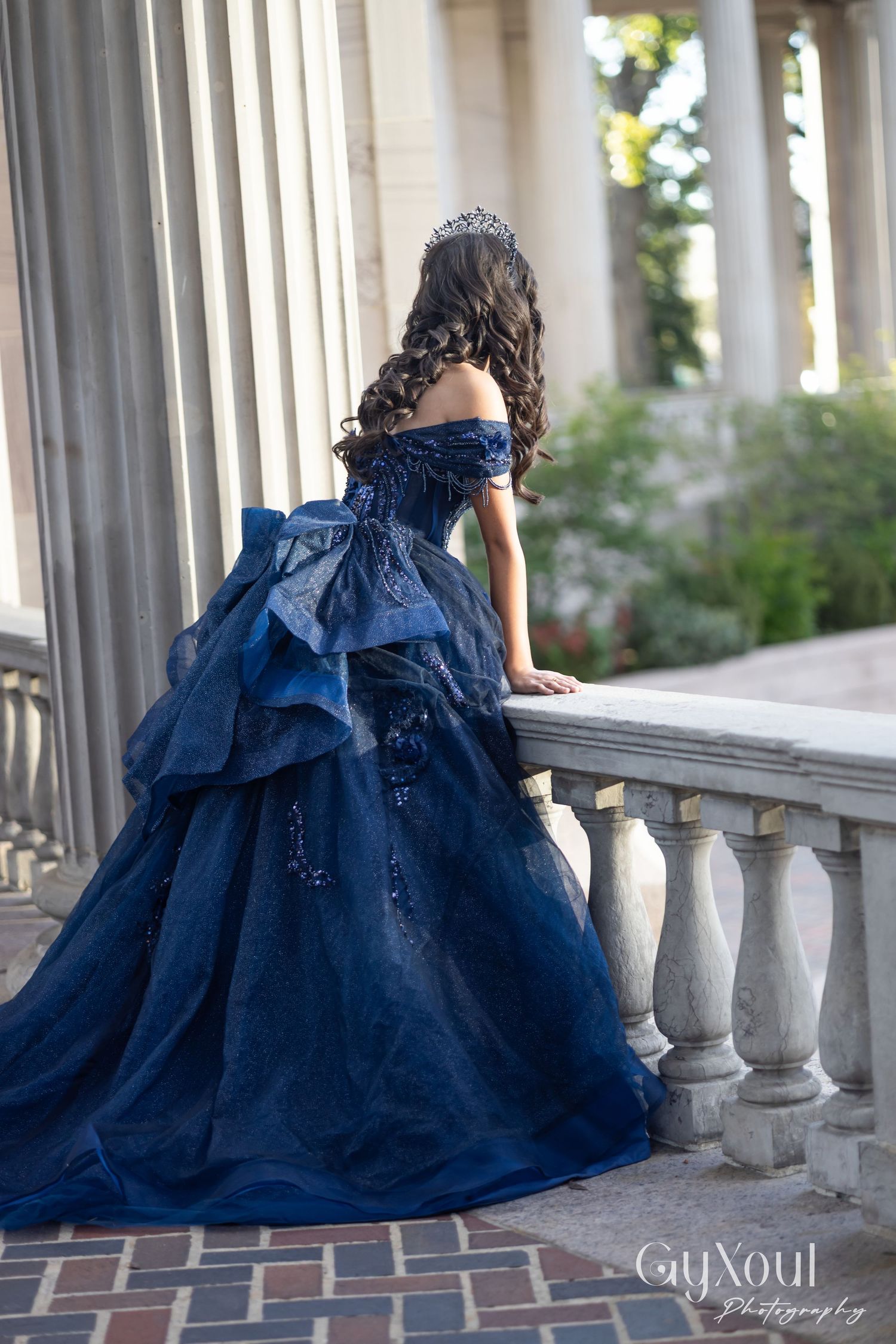 Elegant navy blue ball gown with ruffled details photographed from different angles on a columned porch.
