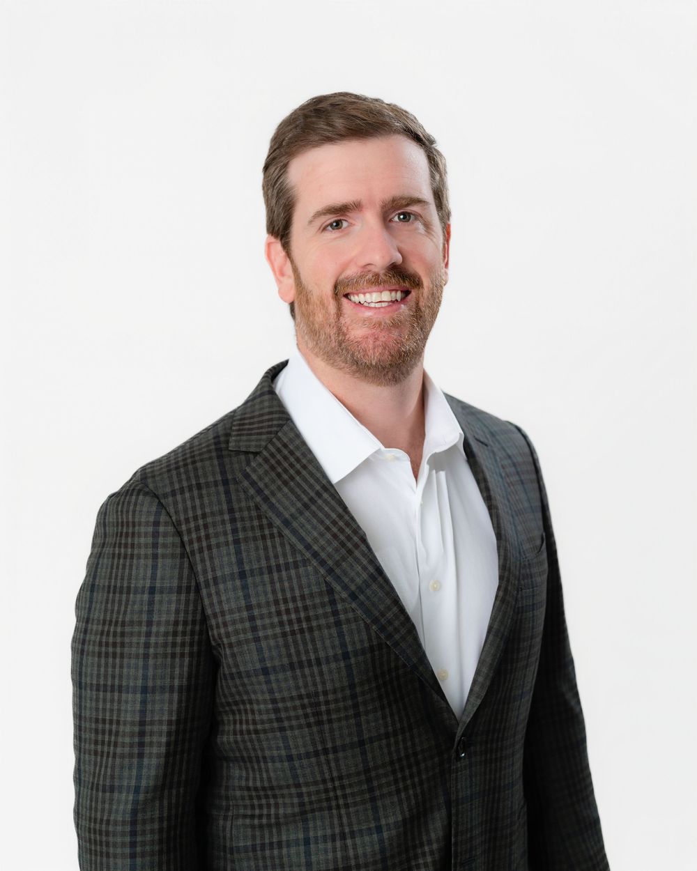 Professional headshot of someone in a checkered blazer and white dress shirt against a light background.