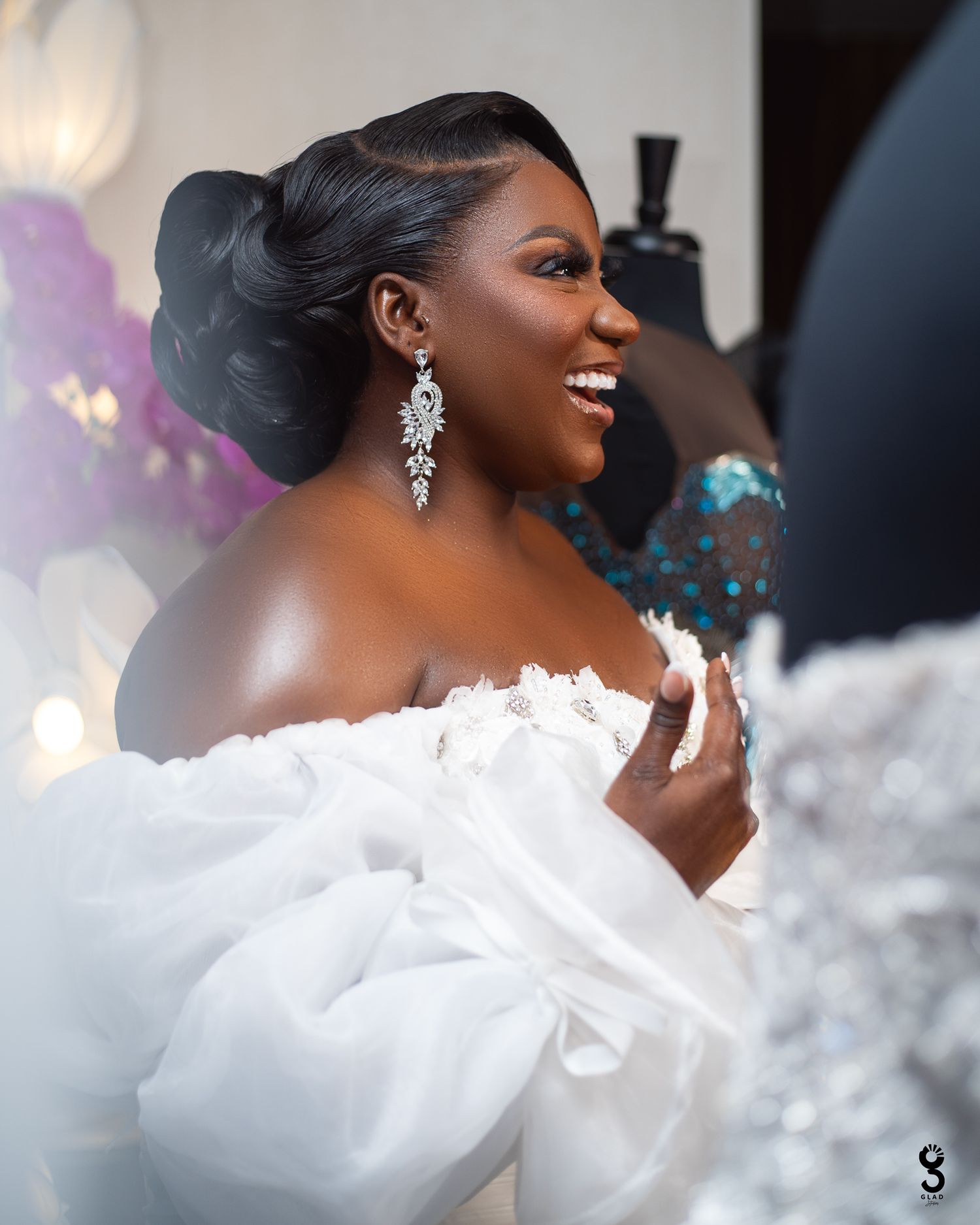 A couple shares an intimate moment at their elegant wedding reception with candlelit tables and gold chairs in the background.