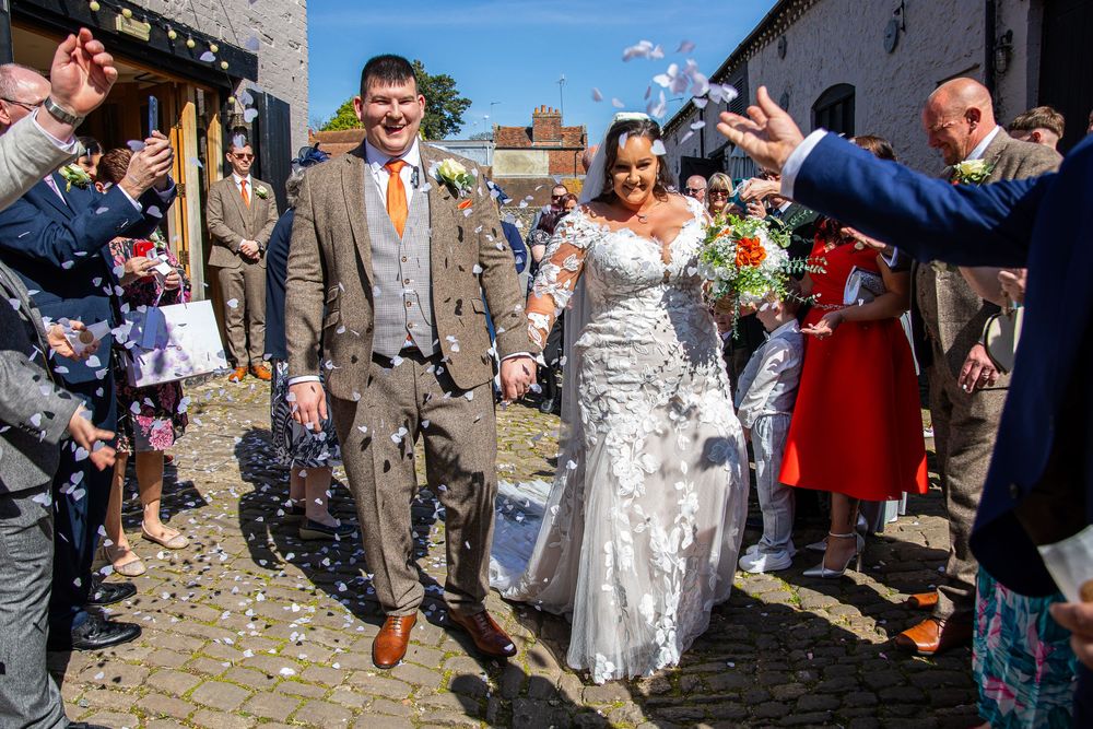 Wedding celebration with confetti being thrown outdoors on a sunny day.