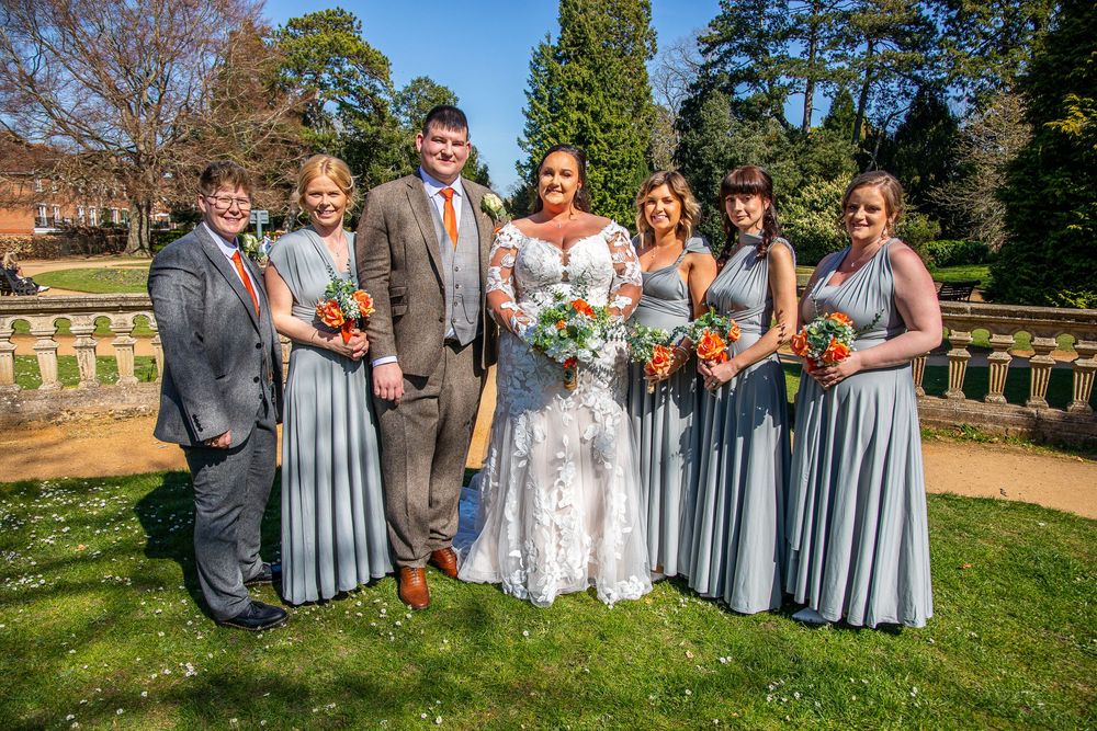 Wedding party in blue and white attire posing for group photos on green lawn.
