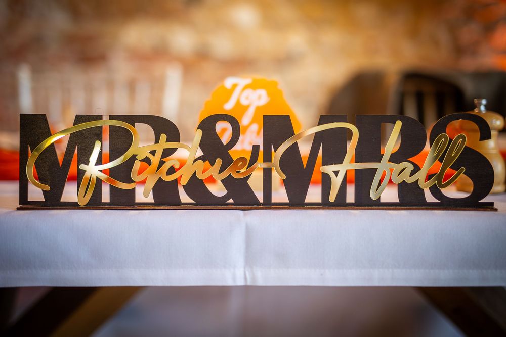 Decorative wedding signage with warm lighting and blurred background.