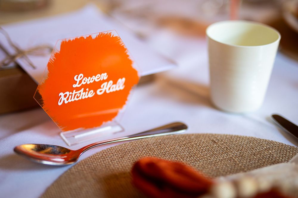 Orange wedding reception place cards and table settings with minimalist design.