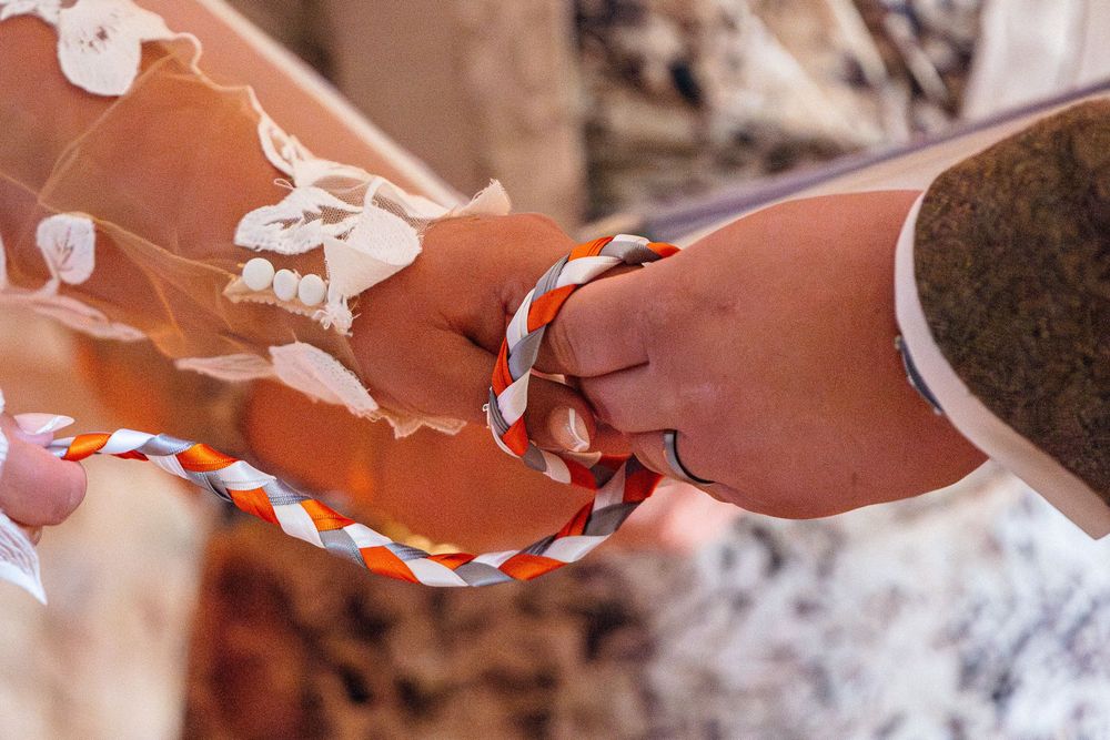 Close-up of hands performing a handfasting ceremony with braided cord.
