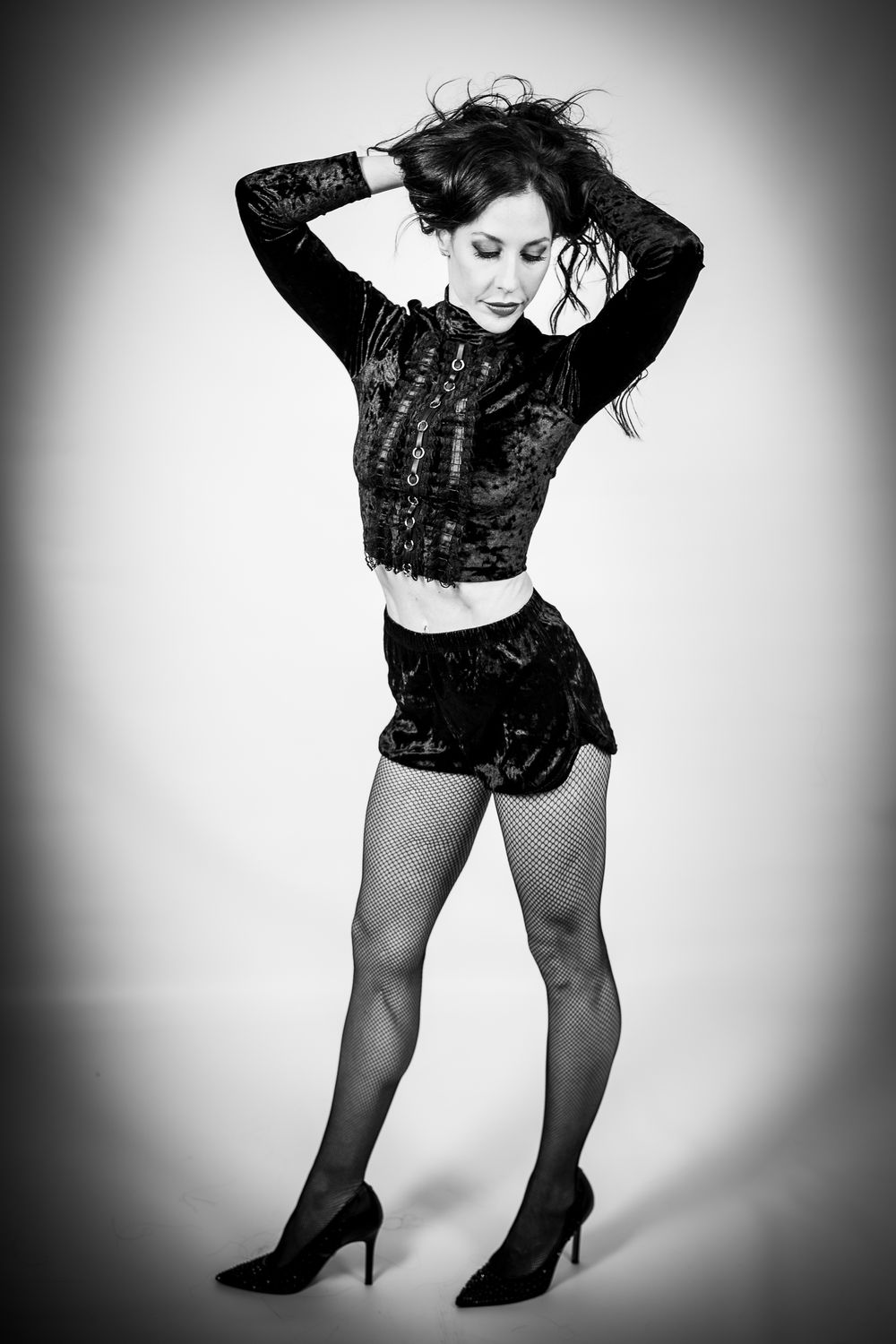 Black and white photo of a model in a lace crop top and shorts striking a dramatic pose.