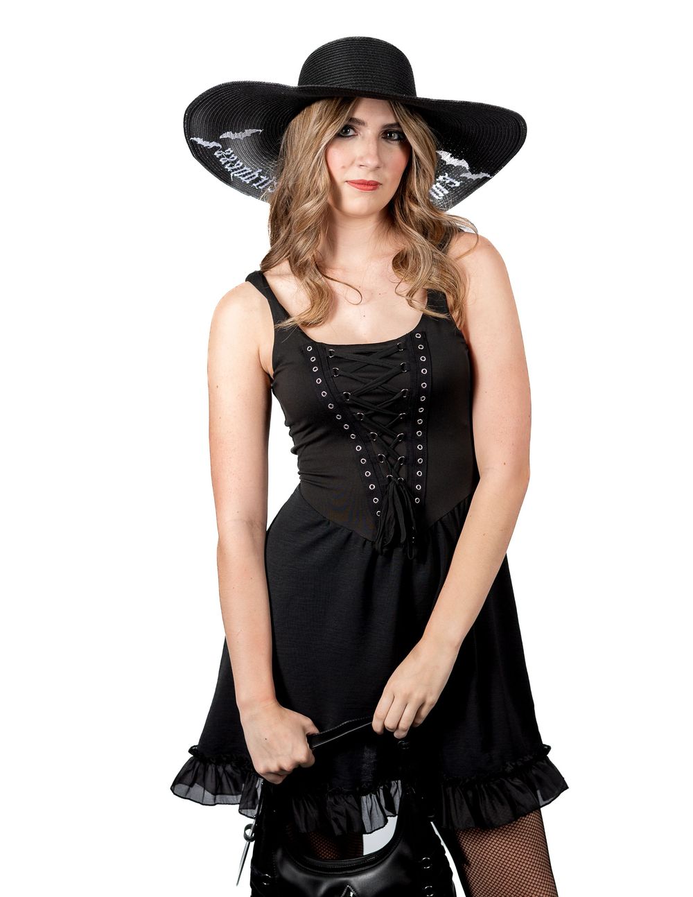 A person in a black gothic dress and wide brimmed hat poses elegantly against a white background.