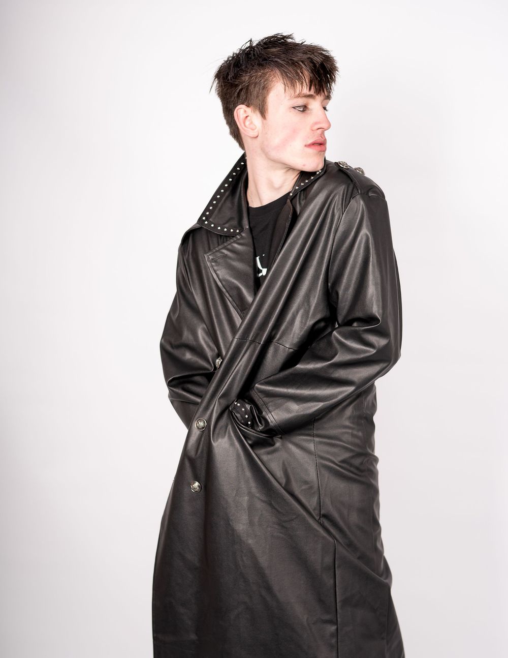 Edgy black leather coat with studded details shown in profile against white background.