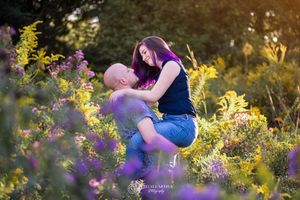 A tender moment captured among blooming yellow wildflowers and purple blossoms at golden hour in a garden setting.