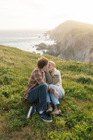 Couple enjoying a romantic moment on coastal cliffs during golden hour.