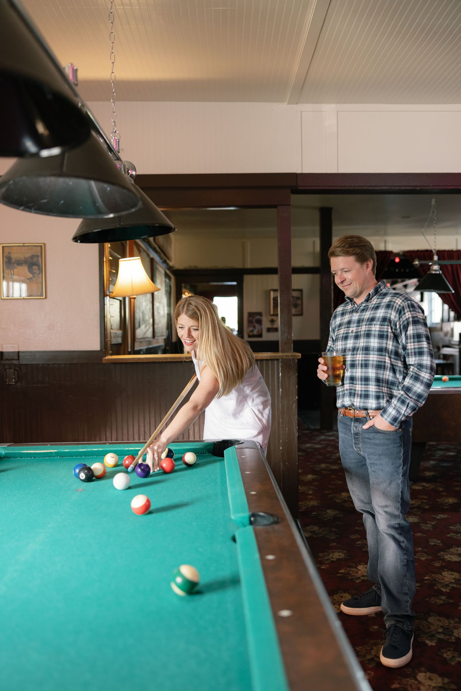 A couple enjoying time together at a pool table in a cozy bar setting.