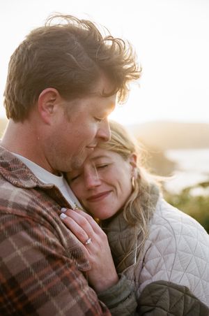 Couple sharing intimate embrace outdoors at sunset with soft golden light illuminating their tender moment.