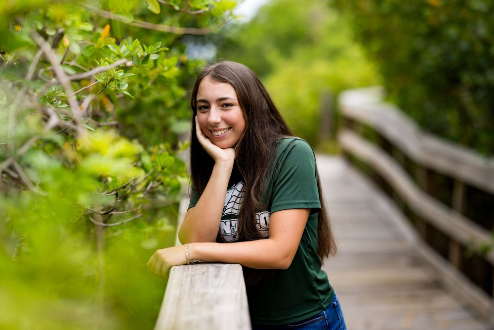 Leaning on wooden boardwalk railing surrounded by lush green foliage. Photos by Tampa Photographer DigitalMyst Photography