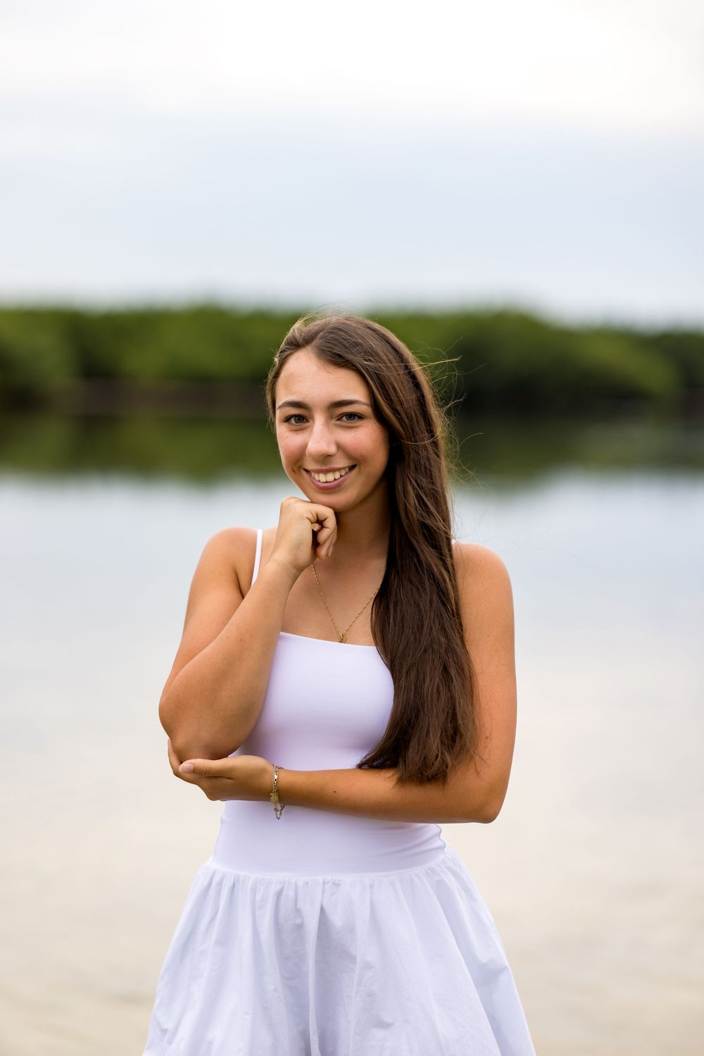 Portrait in white dress against waterfront background with natural lighting.