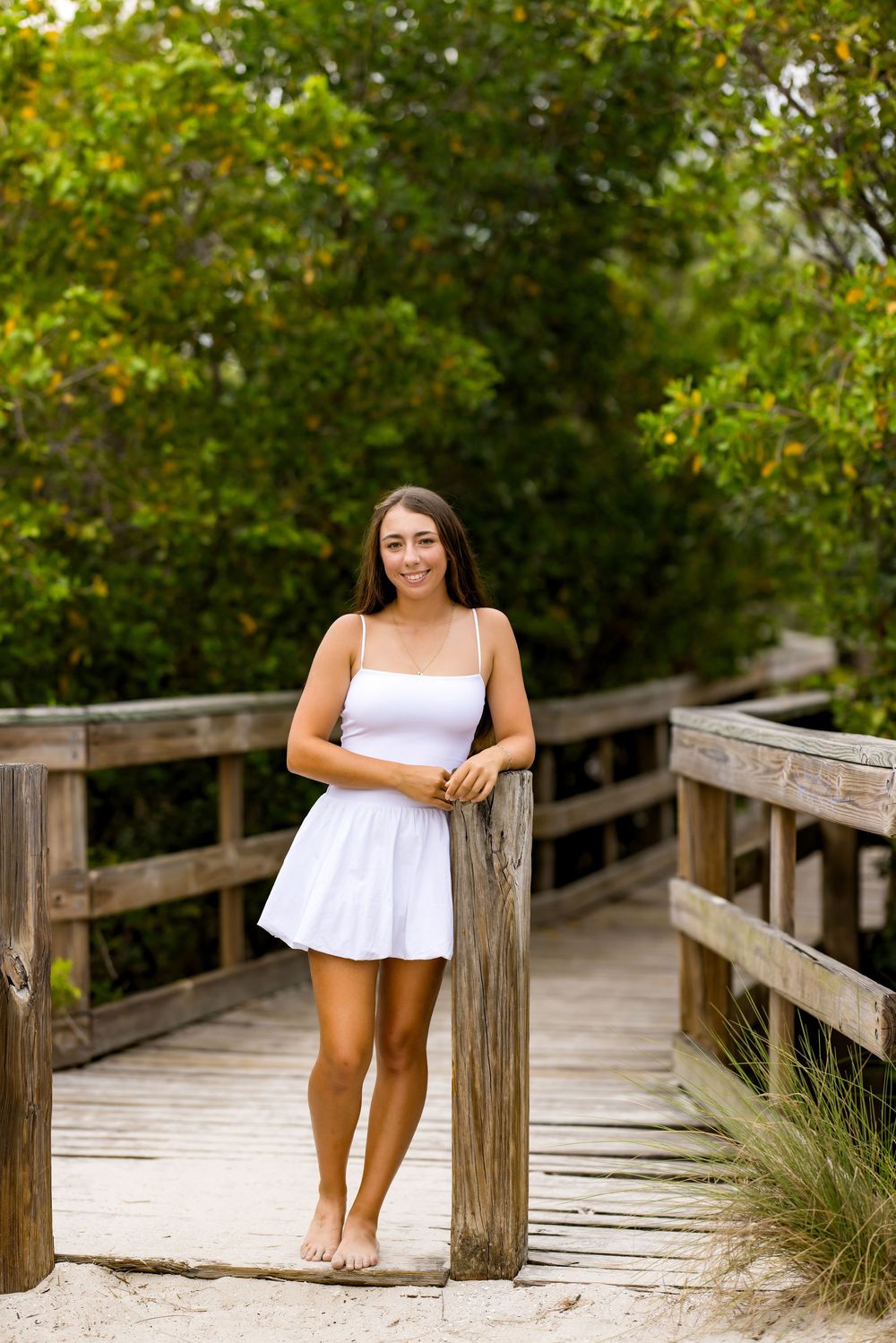 Standing barefoot on wooden boardwalk wearing white summer dress. Photos by Tampa Photographer DigitalMyst Photography