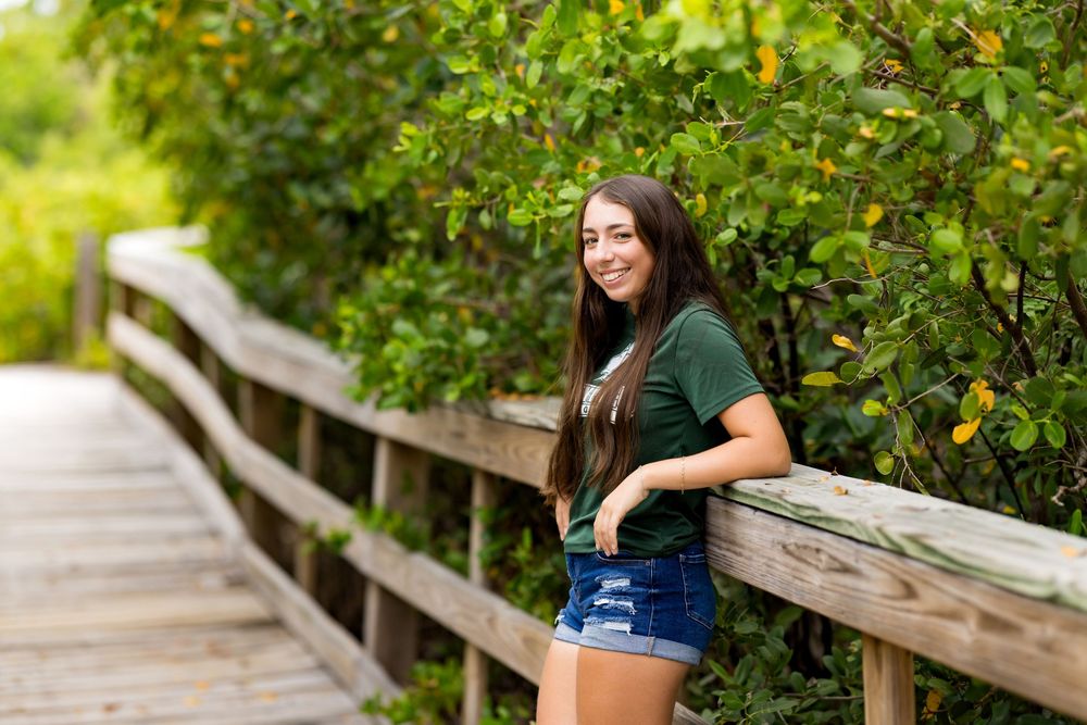 Casual portrait on a wooden boardwalk with green foliage in the background. Photos by Tampa Photographer DigitalMyst Photography