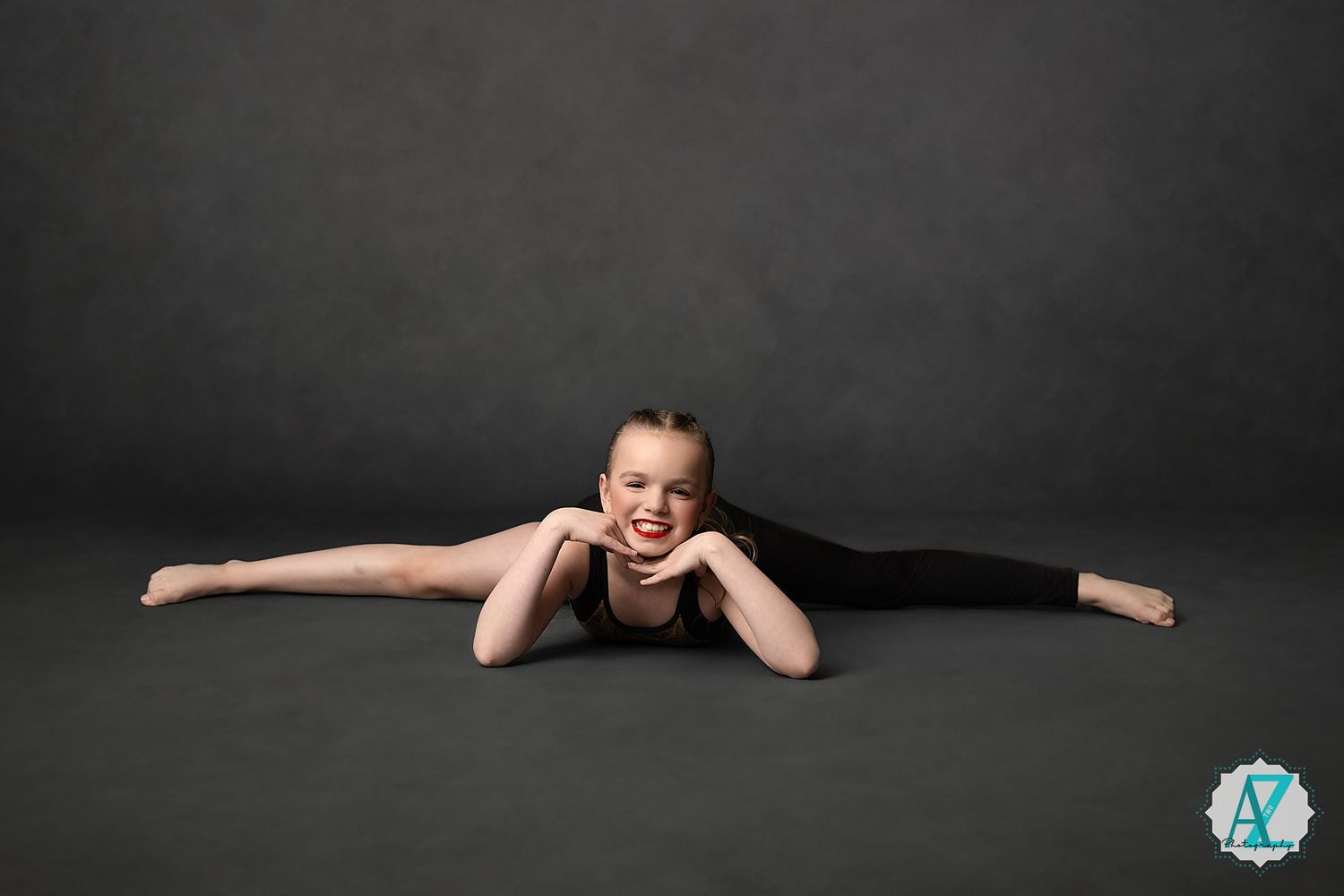 Performer in black leotard practices graceful ballet poses against a dark background.