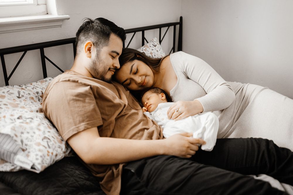San Jose family cuddles in their bed during their Bay Area in-home newborn photography session