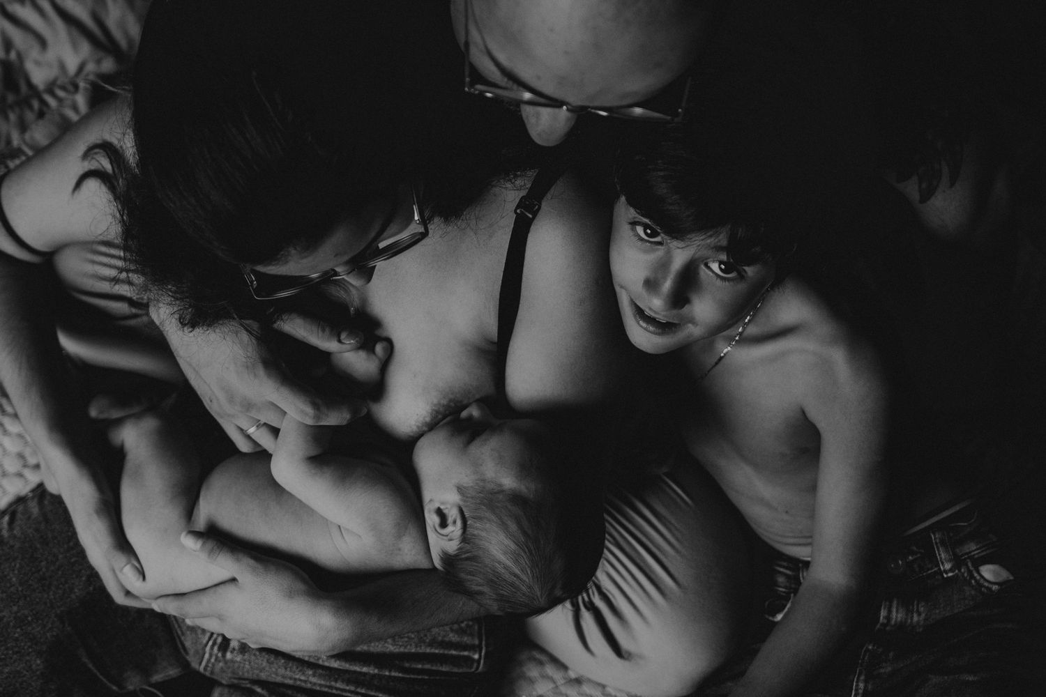 bebé primeiro mês em uma foto em preto e branco numa sessão fotográfica newborn  em casa com o Pai , mãe e irmão mais velho