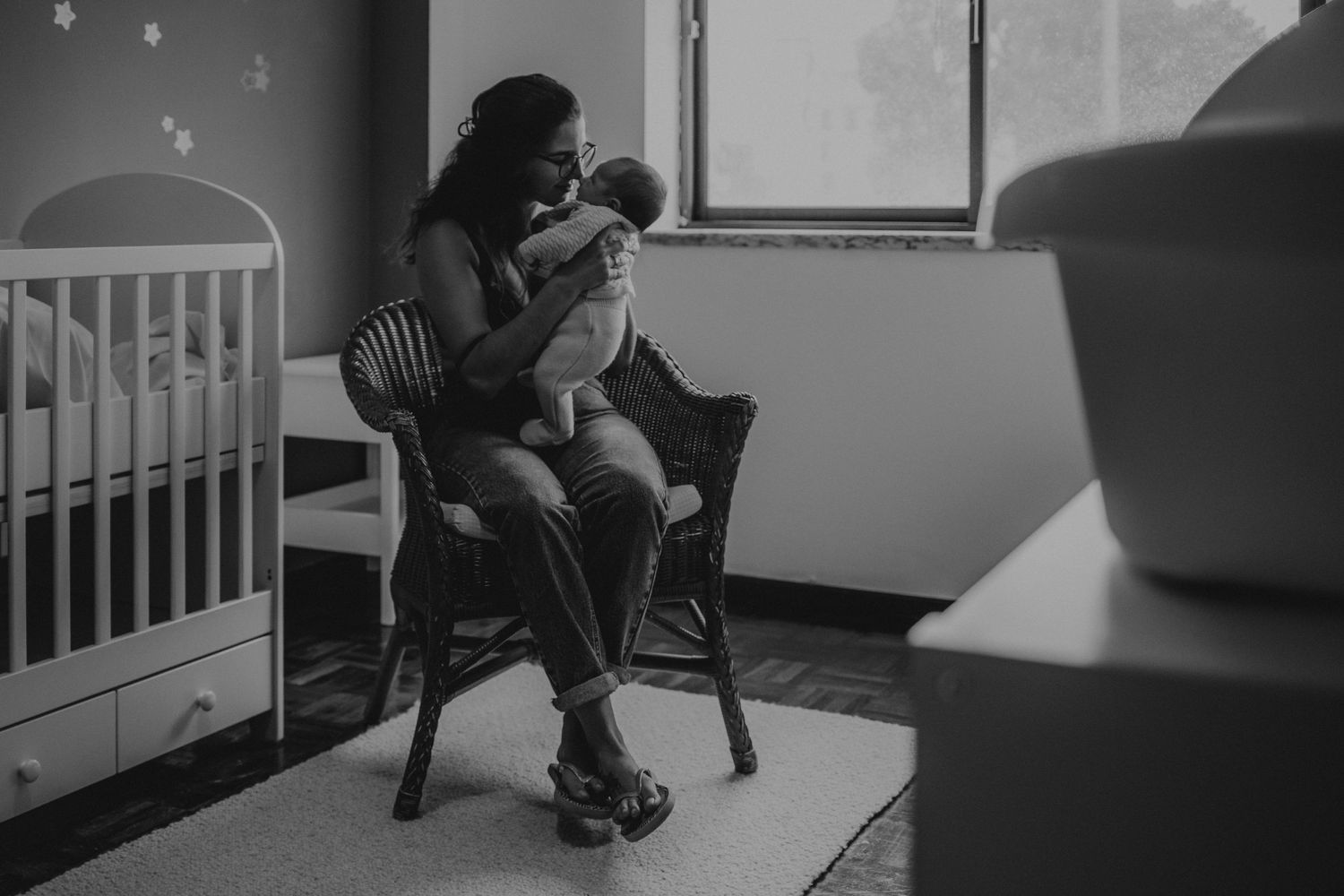 mãe e bebé em casa, foto preto e branco com luz suave sentados em cadeira, momento de afeto numa sessão fotográfica de família casa Portugal