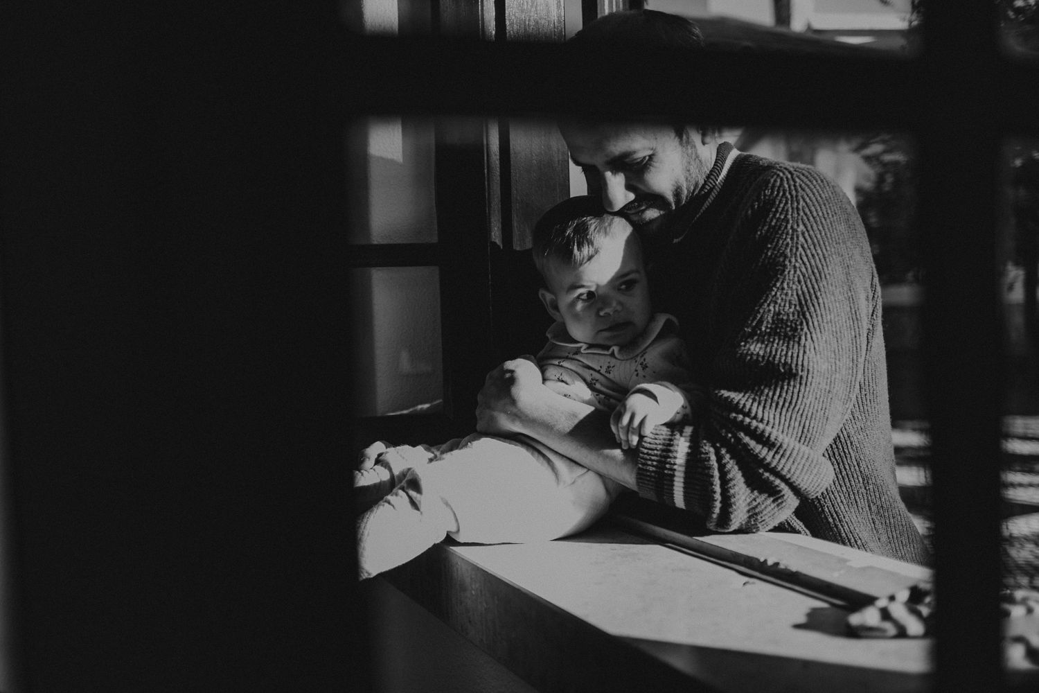 Pai e filha sentados na janela em uma foto preto e branco luz dura em uma sessão de familia em Portugal