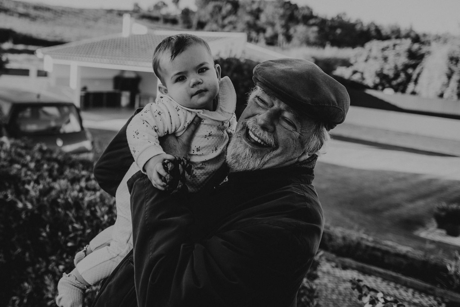 Bebé no colo do avô super feliz em uma foto em preto e branco no jardim da casa numa sessão de familia em Portugal , Óbidos