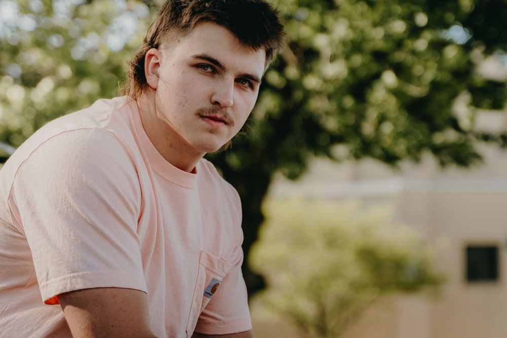 Outdoor Senior Portrait in pale pink t-shirt with natural lighting and blurred background - Warsaw, Indiana