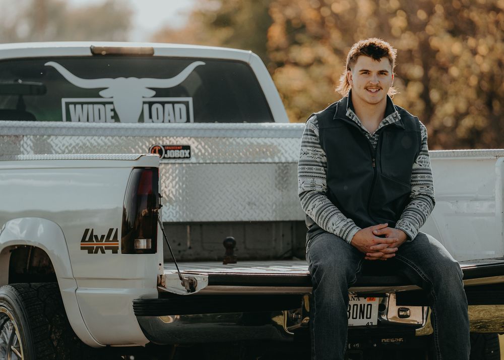 Senior Portrait sitting on tailgate of pickup truck with custom wheels during sunset - Warsaw, Indiana