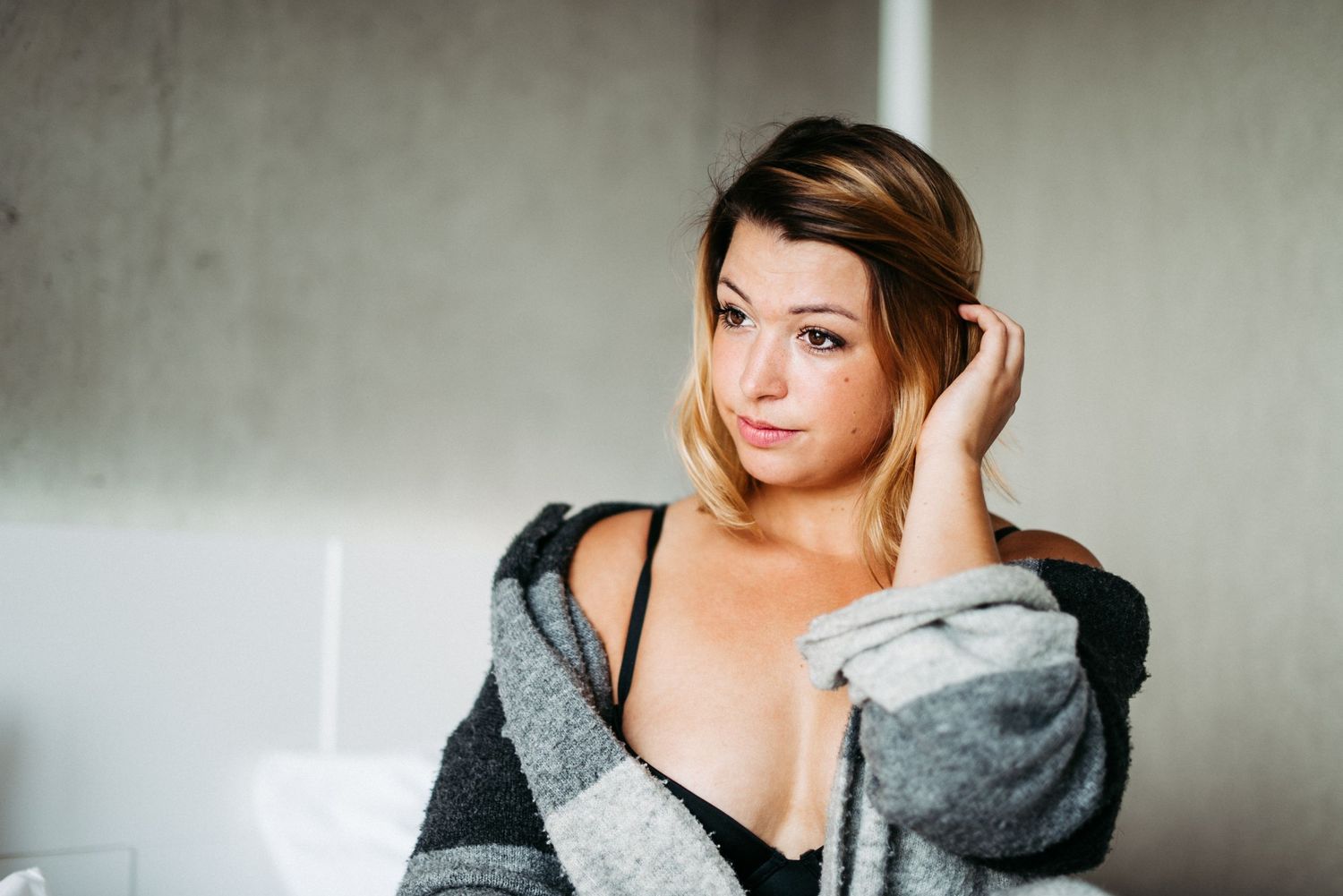 Eine bezaubernde Frau in einem kuscheligen Cardigan posiert für ein Boudoir Foto und präsentiert ihre Schönheit in atemberaubenden Foto.
