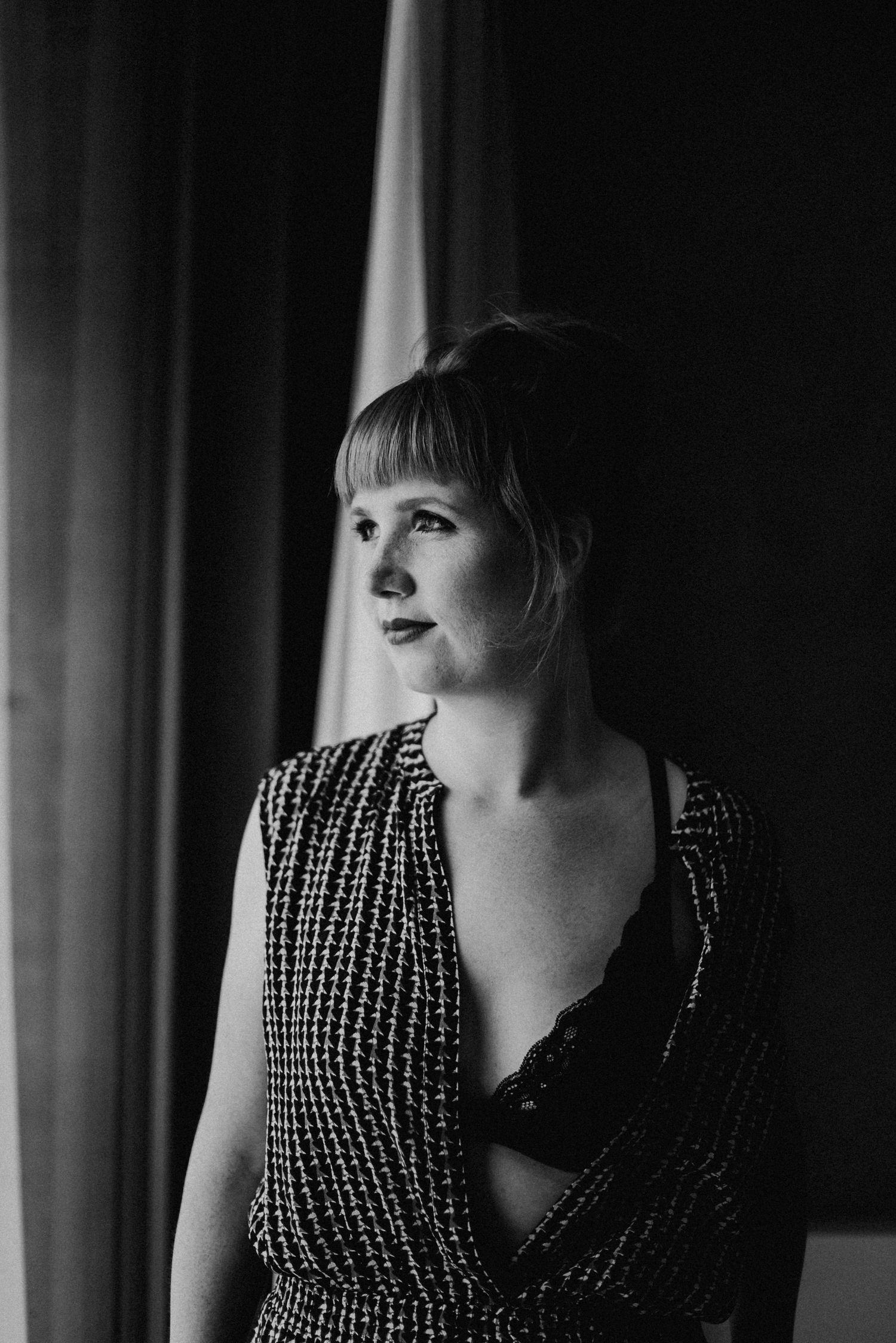 Schwarz-Weiss Boudoirfoto zeit eine Frau in schwarzer Unterwäsche. Sie schaut zur Seite.