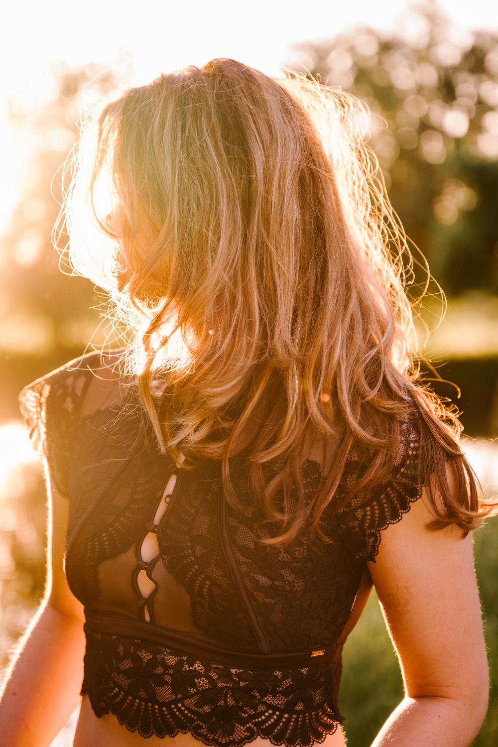 Silhouette of flowing hair backlit by golden sunlight creating a dreamy ethereal glow against dark background.