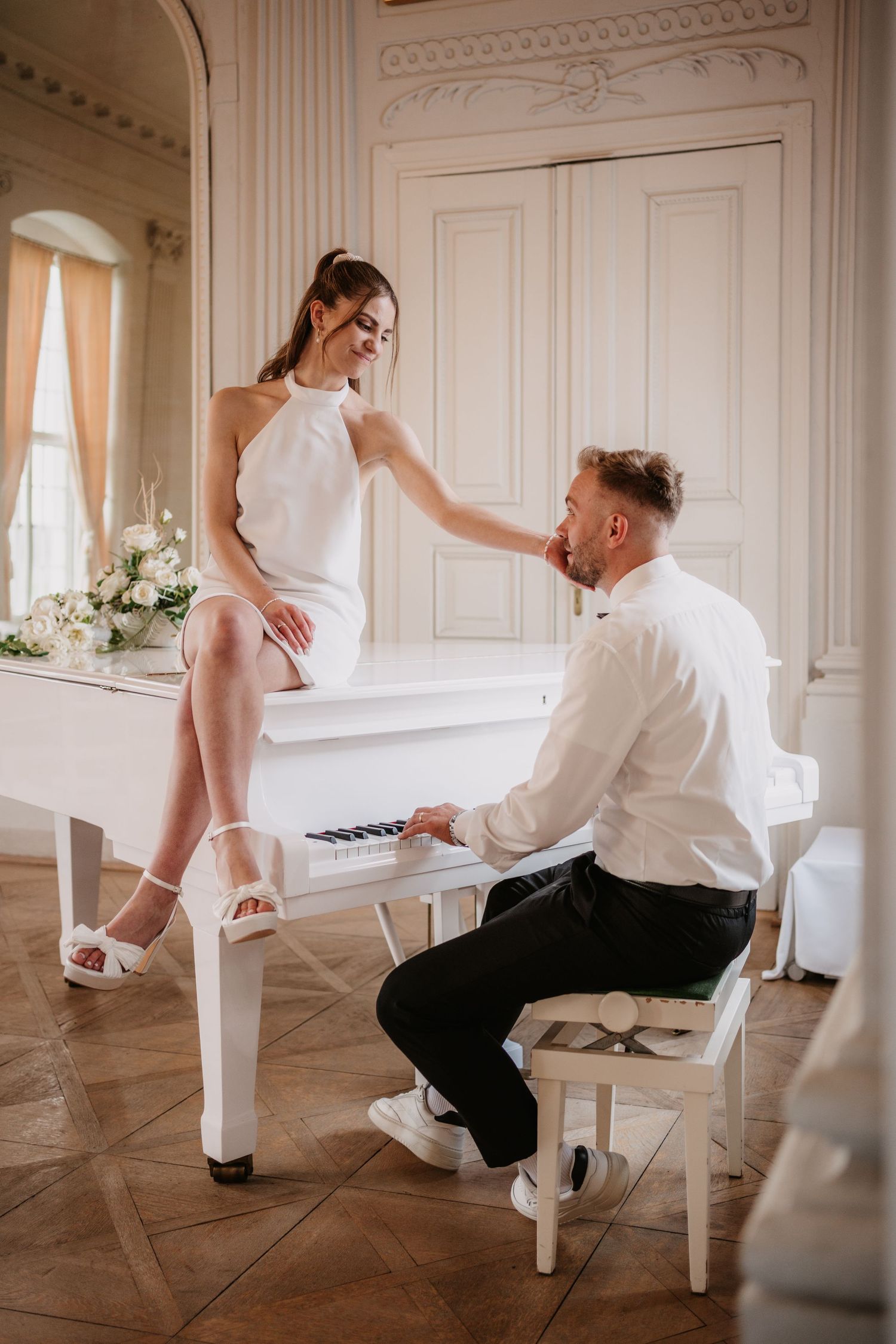 Romantic moment with piano in elegant white room featuring vintage interior and floral decorations.