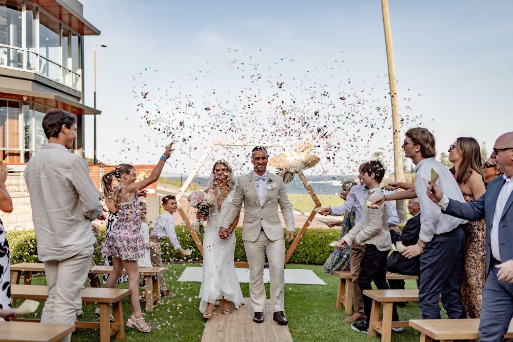 A series of wedding guests celebrating outdoors with paper confetti and cheers at a beachside venue.