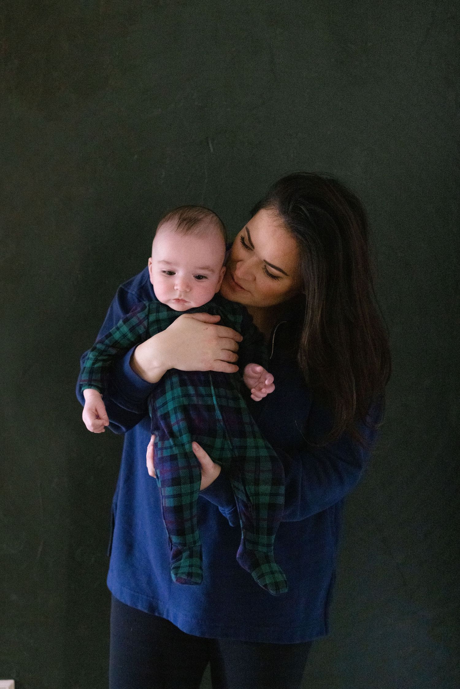 A series of tender moments between a parent and baby against a dark backdrop.