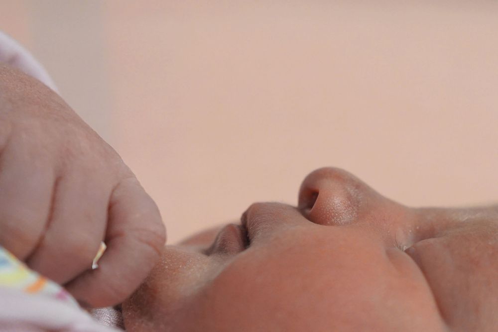 Close up view of a small baby taking a bottle while feeding.