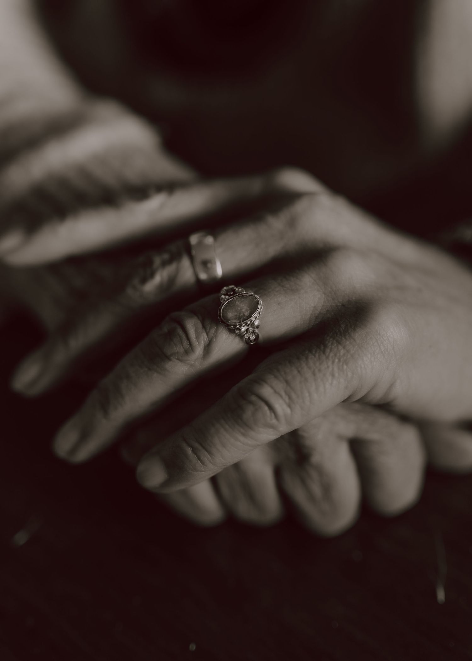 Black and white close-up photo of hands touching, creating an intimate and artistic composition in low light.