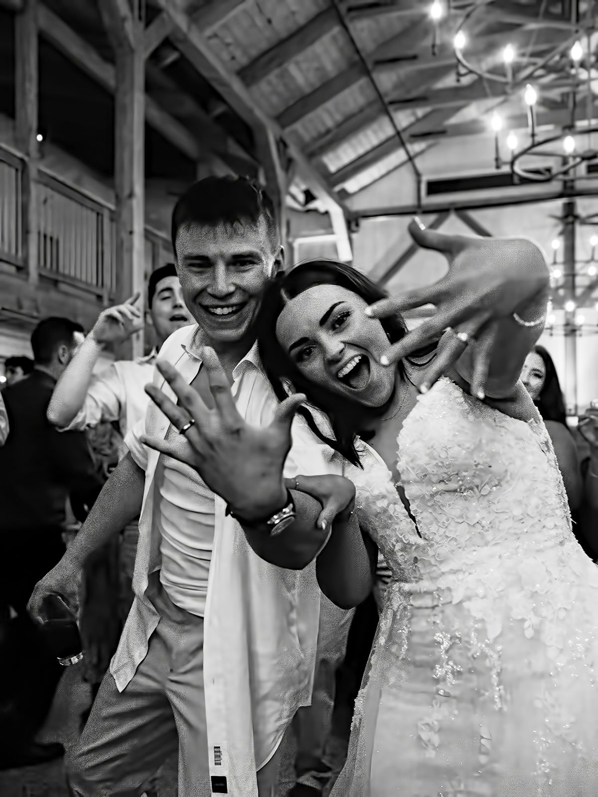 Joyful black and white reception photo of couple showing off wedding rings on the dancefloor at The Tannery Barn.