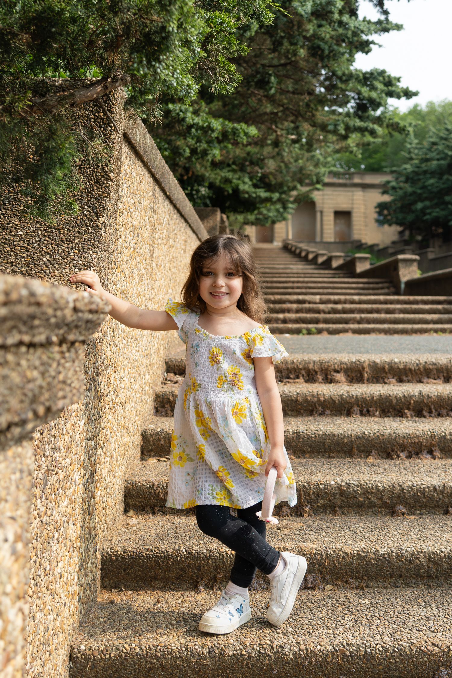 Little girl smiling on stone staircase outdoors — playful child lifestyle photography