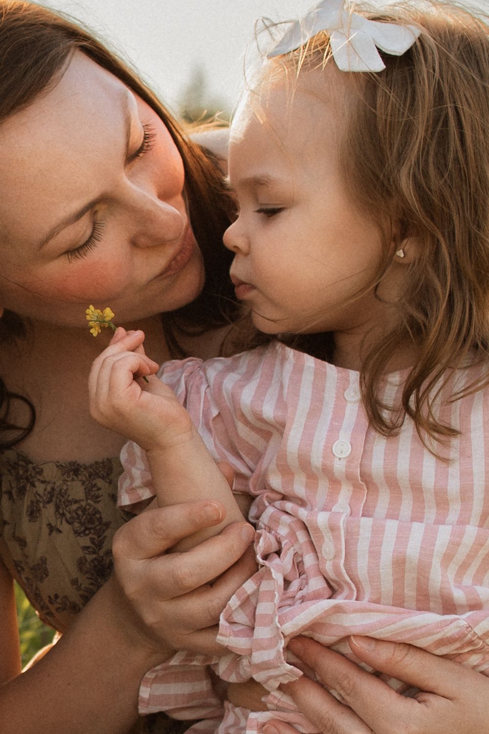 Tender moment between loved ones sharing gentle closeness outdoors in warm sunlight.