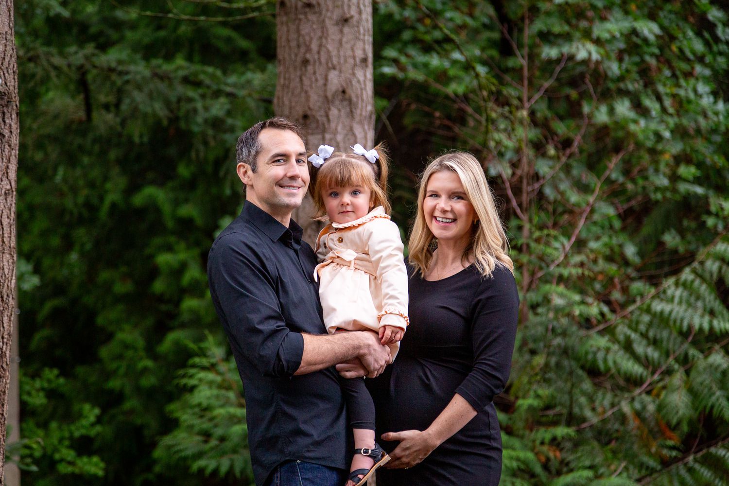 Relaxed outdoor family portrait session showing playful interaction in a lush forest setting.