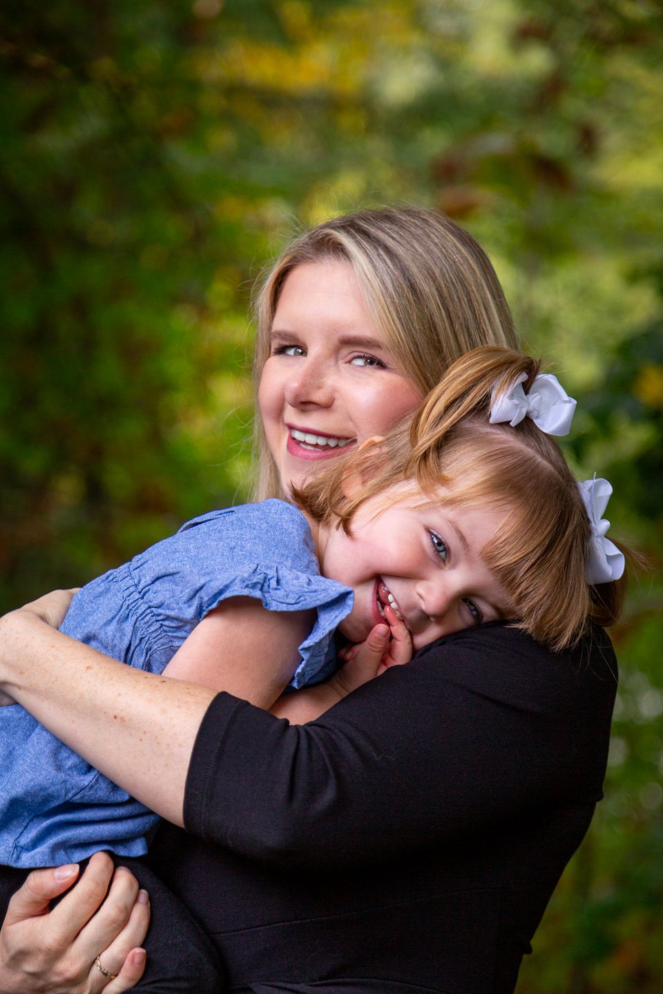 A sweet embrace between adult and child outdoors with natural bokeh background during autumn photoshoot.